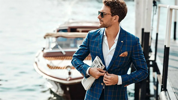 Blog - Real Photgraphy of a chic man puts his jacket back on in front of a riva. BOOCLE